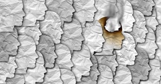 many paper face silhouettes, one is charred